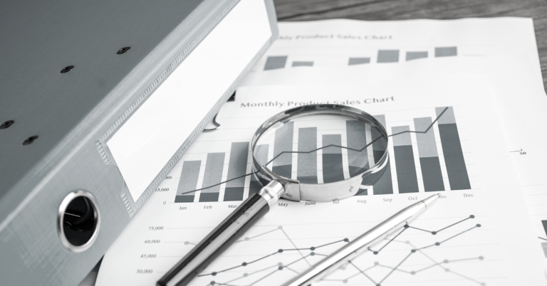 Magnifying glass on monthly product sales chart report